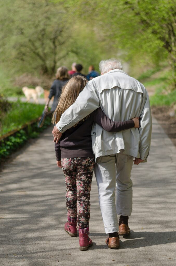 Grandfather and granddaughter walking in the park