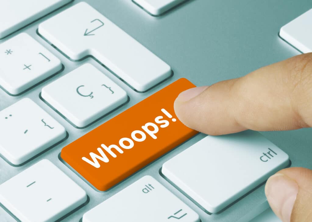 Person hitting a "Whoops!" button on a computer keyword.