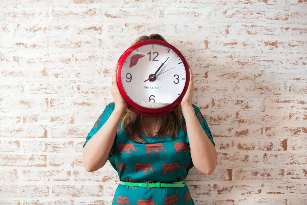 Woman holding a clock in front of her face