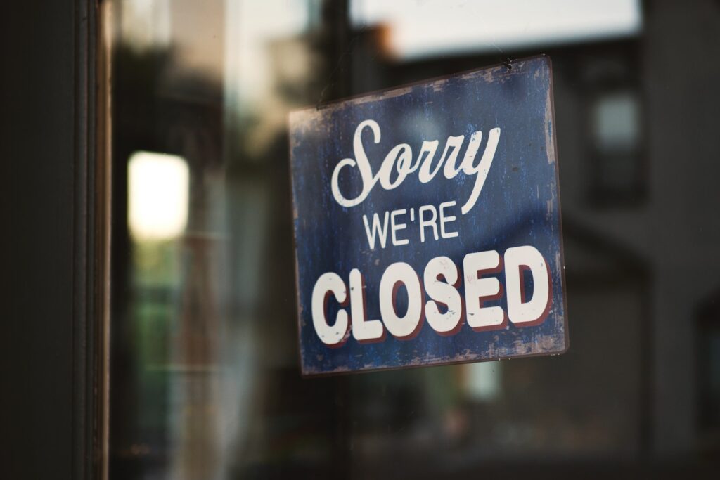 Sorry We're Closed sign hanging in storefront window.