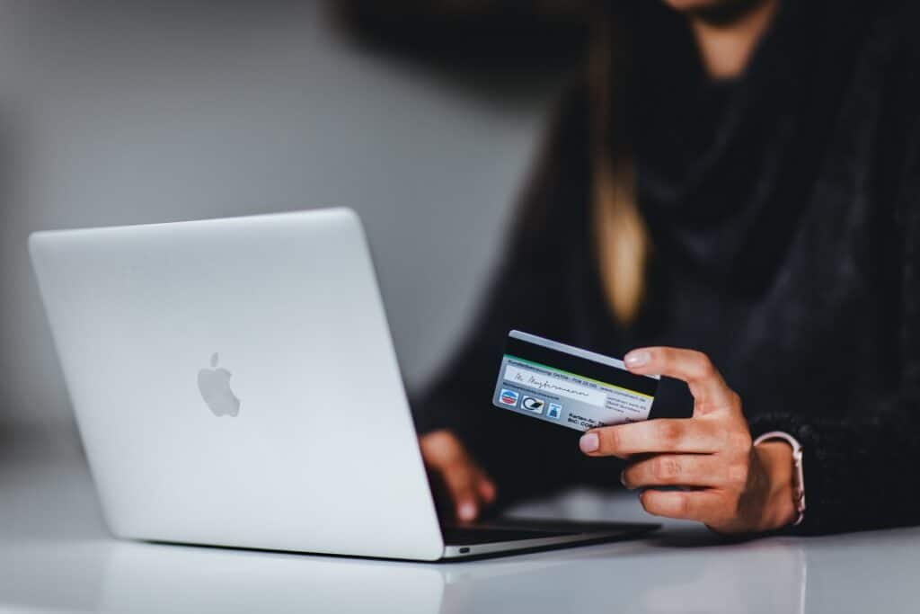 Person holding credit card while looking at laptop computer screen.