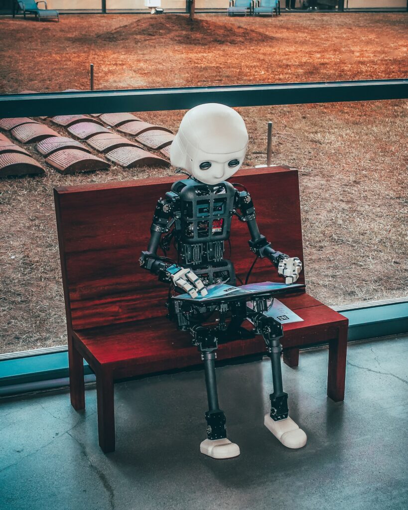 Robot sitting on a bench looking at a tablet to emphasize compliance management and automation.