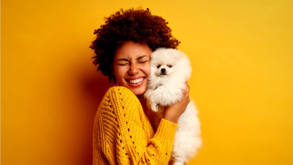 Woman enthusiastically hugs her dog.