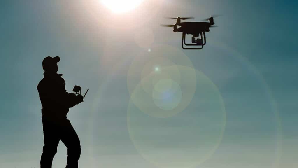 Silhouette of person flying a drone on a sunny, clear day
