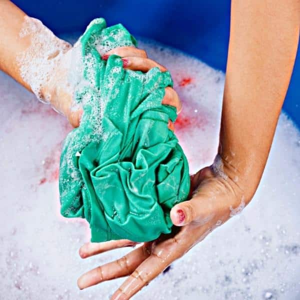 Close-up of person wringing out a dish cloth as a metaphor for the churning and twisting of insurance contracts.