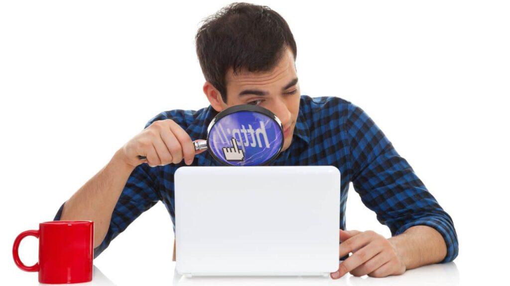 Person looking through a magnifying glass at a tablet screen