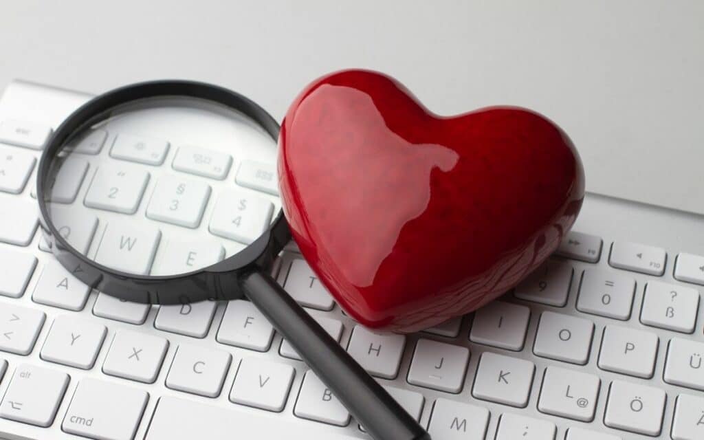 Heart paperweight and magnifying glass sitting atop a computer keyboard